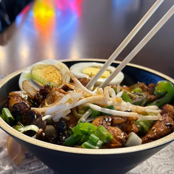 Itokos Grill's Japanese dish with chicken, vegetables, bean sprouts, and hard-boiled eggs, with chopsticks.