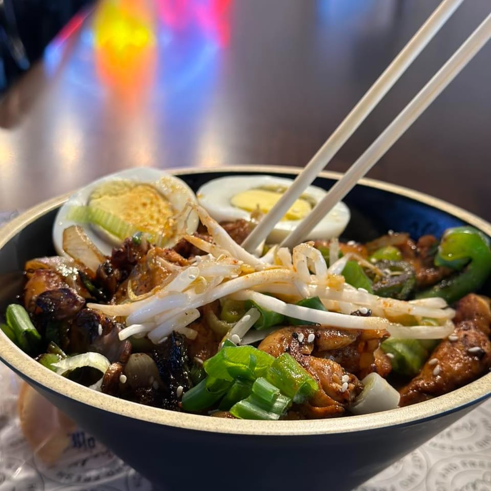 Itokos Grill's Japanese dish with chicken, vegetables, bean sprouts, and hard-boiled eggs, with chopsticks.