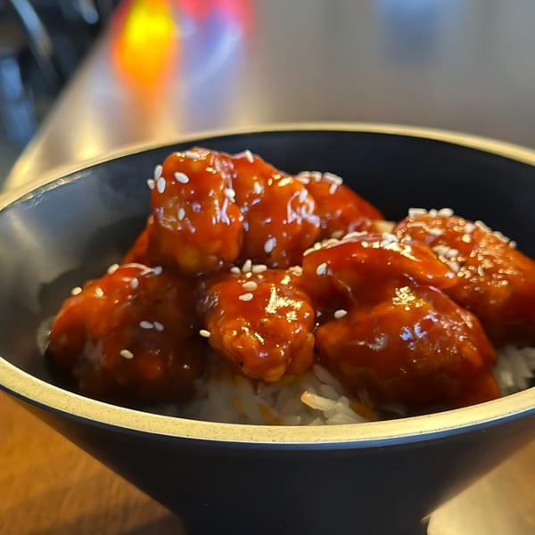 Itokos Grill's sweet and sour chicken, topped with sesame seeds, served over white rice in a black bowl.